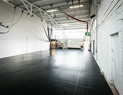 Das Studio im Q-Space mit schwarzem Tanzboden und weißen Wänden. Von der Decke hängen diverse Seile und Tücher.