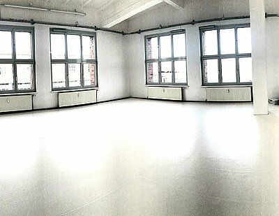 Gezeigt ist ein Studio im Seneca Berlin. Zwei Wände haben mehrere große Fenster. Der Boden ist hell.
