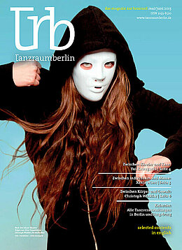 Das Titelblatt des Magazins im Mai 2013 zeigt eine Person mit schwarzem Kapuzenpulli und langen roten Haaren. Sie trägt eine weiße Vollgesichtsmaske. Der Hintergrund ist hellblau.